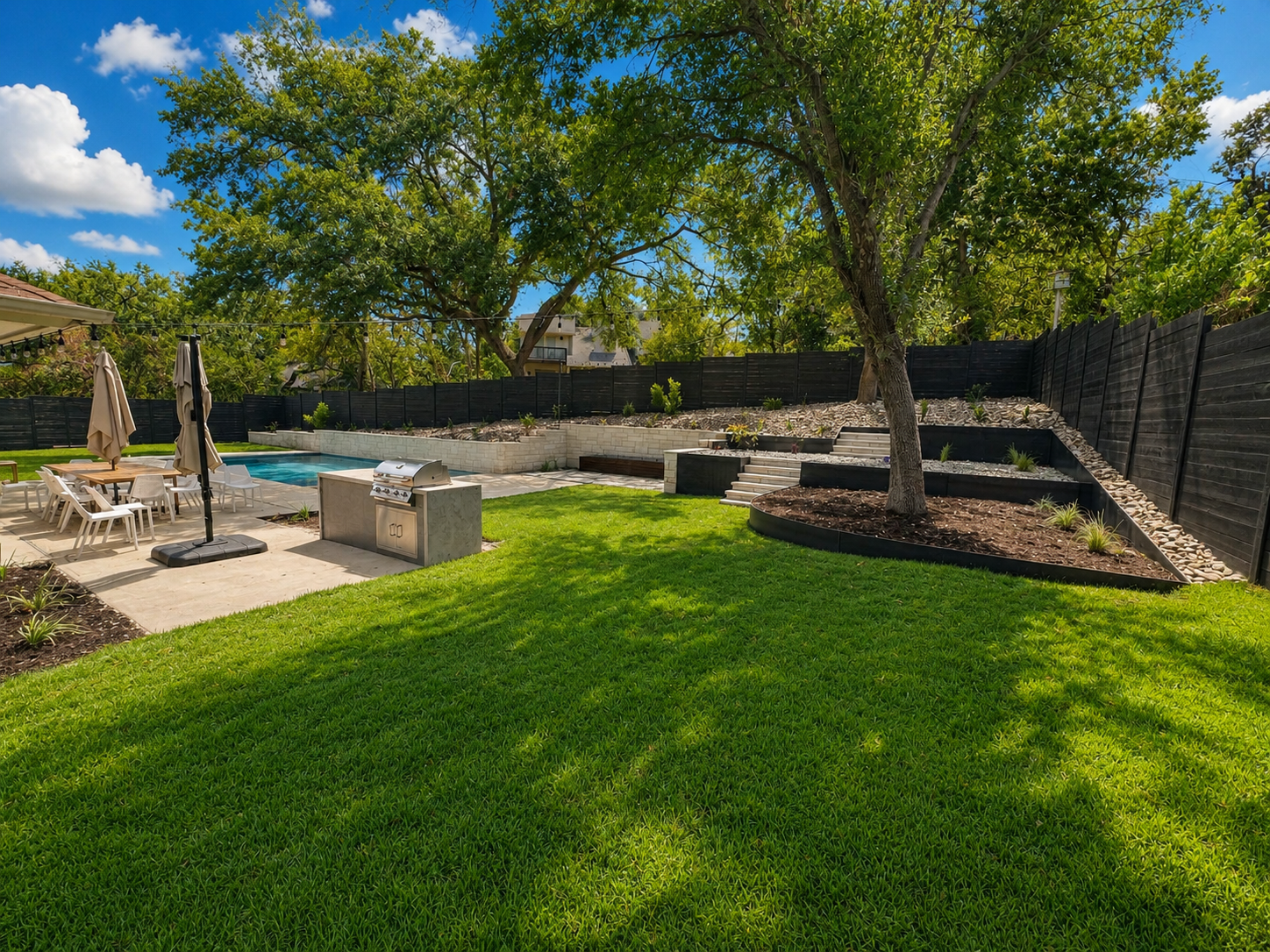 Backyard pool with tiered rock retaining wall and lush lawn